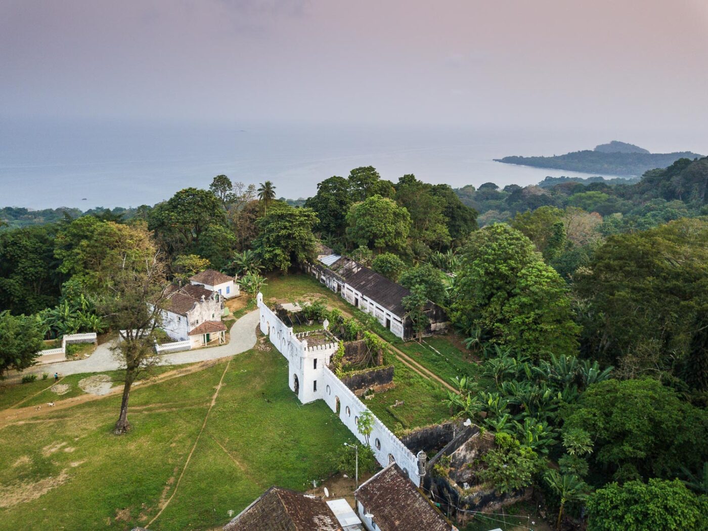 Reise in Sao Tome und Principe in Afrika. Aus der Luft blickt man auf das ehemalige, weisse Plantagenhaus des heutigen Hotels Roca Sundy herab. In der Ferne liegt hinter dem Urwald das Meer.