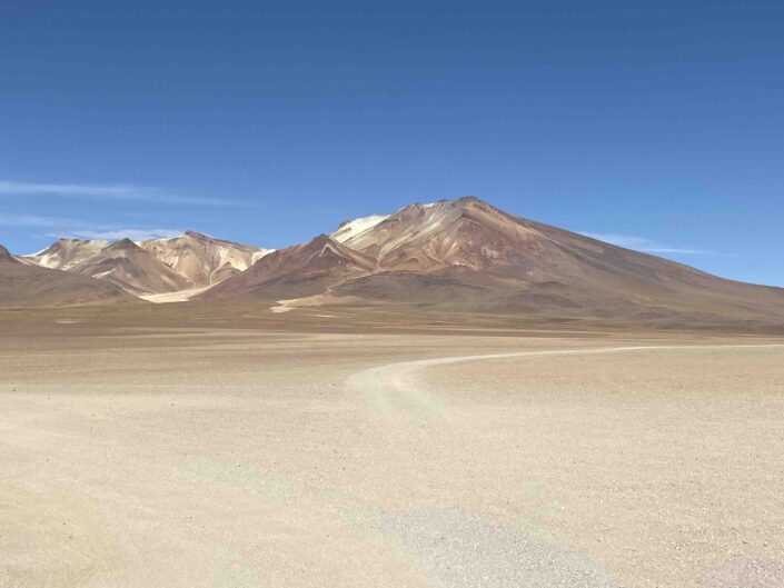 Reise in Bolivien in Südamerika. Hinter einer Wüste im Altiplano Hochland ragen die Anden empor.