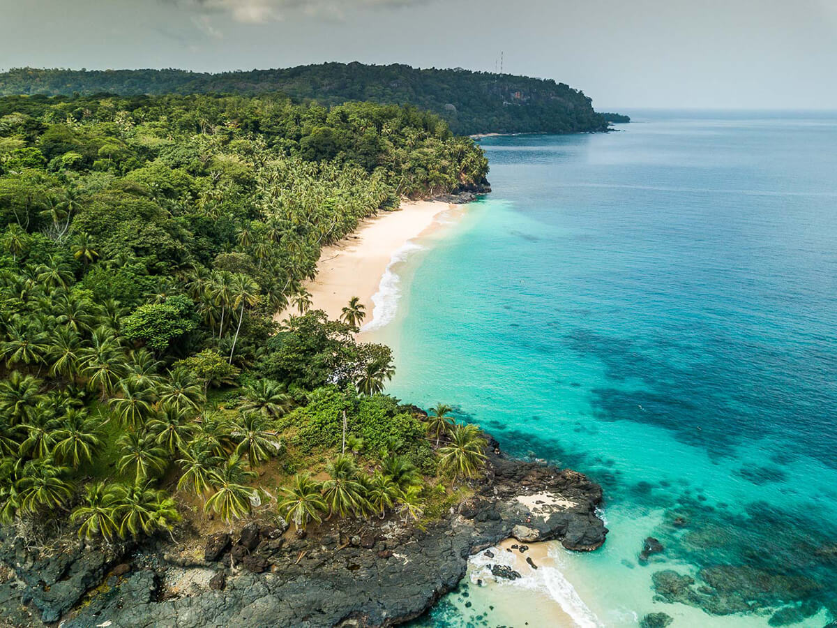 Reise in Sao Tome und Principe in Afrika. Blick auf die Insel Principe aus der Luft, man sieht hellen Sandstrand, das türkisfarbene Meer und zahlreiche Palmen.