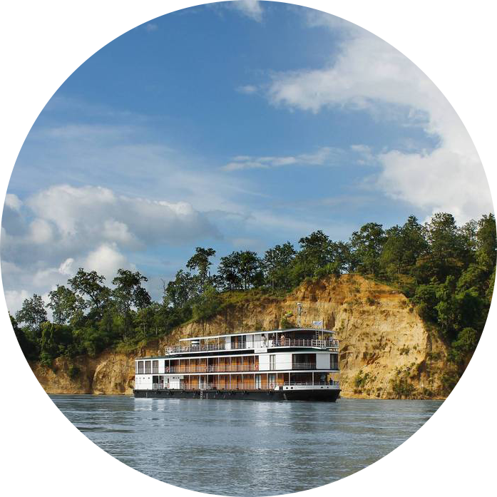 Reise in Myanmar in Asien. Das Schiff Thurgau Exotic 3 von Thurgau Travel fährt dem Fluss Irrawaddy in Myanmar entlang, im Hintergrund erhebt sich eine Felswand.