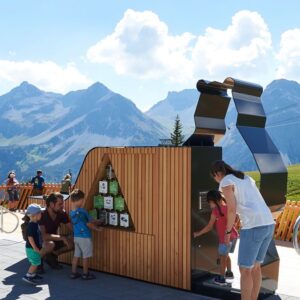 Reise in der Schweiz in Europa. Eine Familie (Eltern mit drei Kindern) untersucht einen Posten beim Bärenpark in Arosa, im Hintergrund ist das beeindruckende Panorama zu sehen.