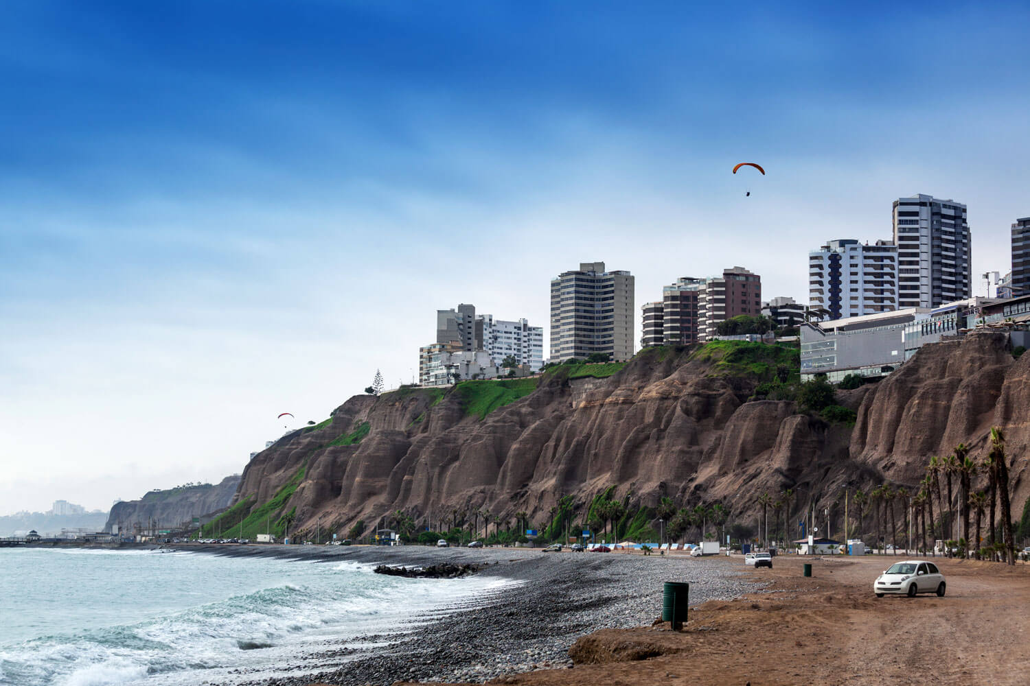 Pazifikküste vor Lima mit Meer und Strand. Im Hintergrund Skyline der Stadt und Gleitschirm.