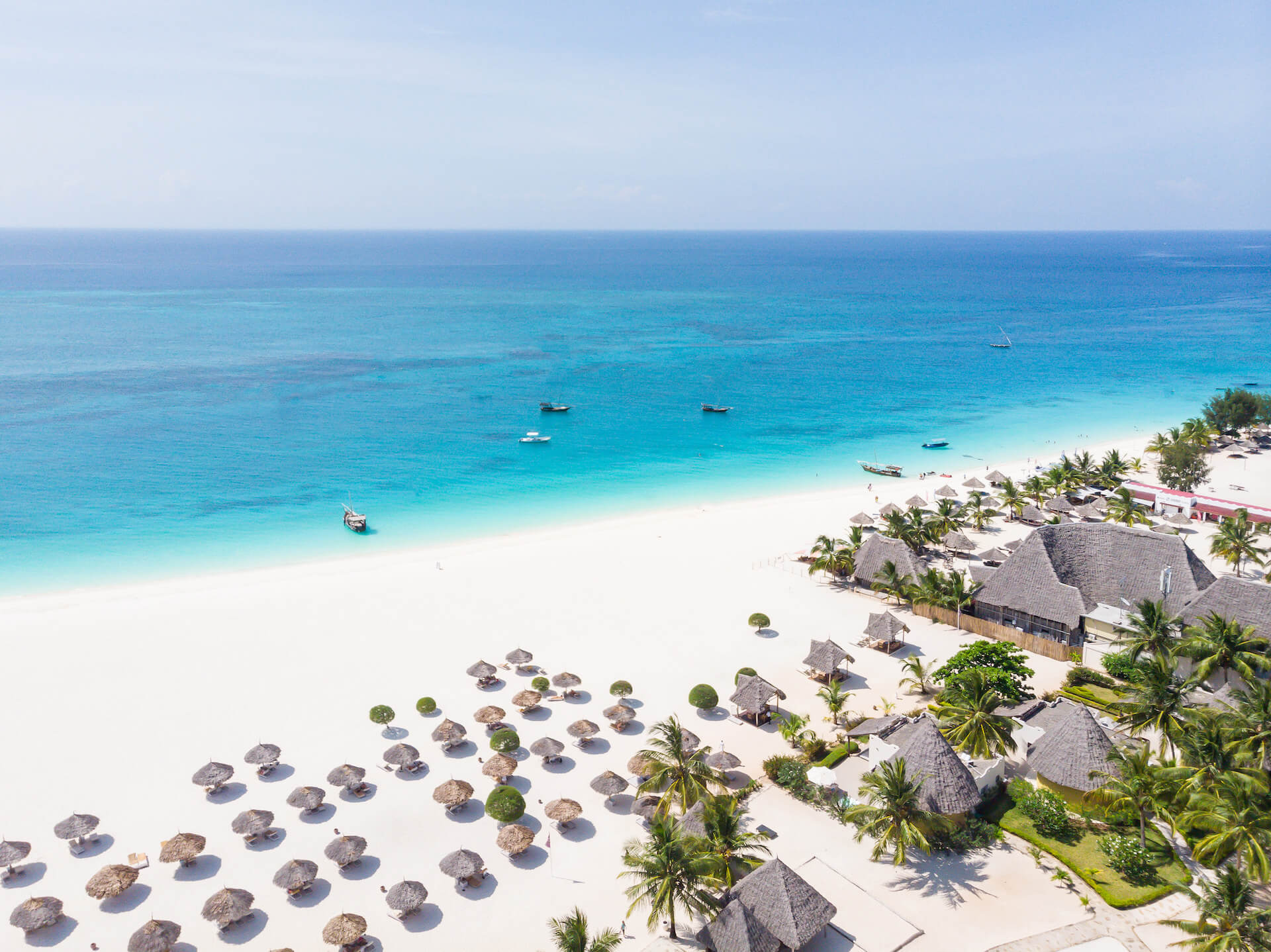 Strand vom Hotel Gold Zanzibar mit Strandschirmen, weissem Sand und türkisfarbigem Wasser