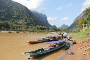 Fluss mit zwei traditionellen Holzbooten vor grüner Landschaft.